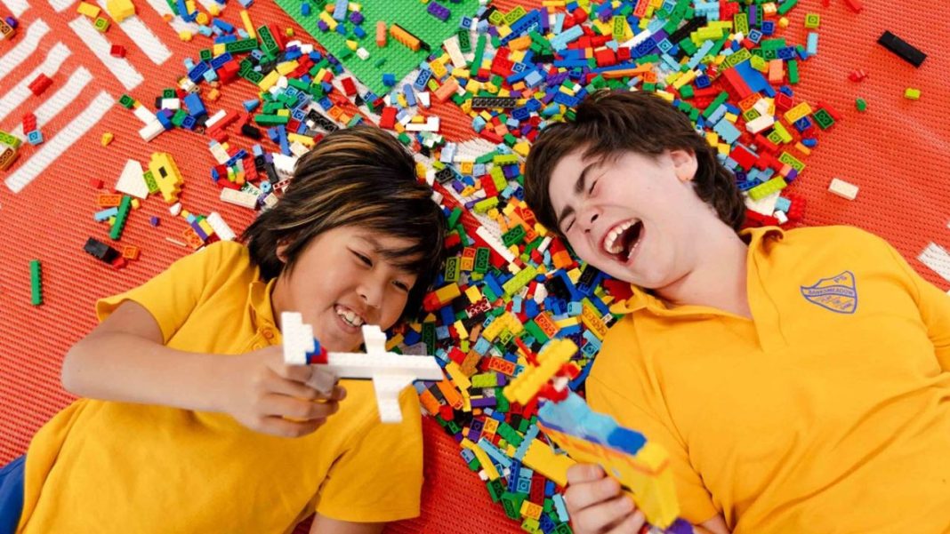 Duas crianças rindo e brincando com blocos de montar coloridos, acompanhando o Dia Internacional da Brincadeira estabelecido pela ONU.